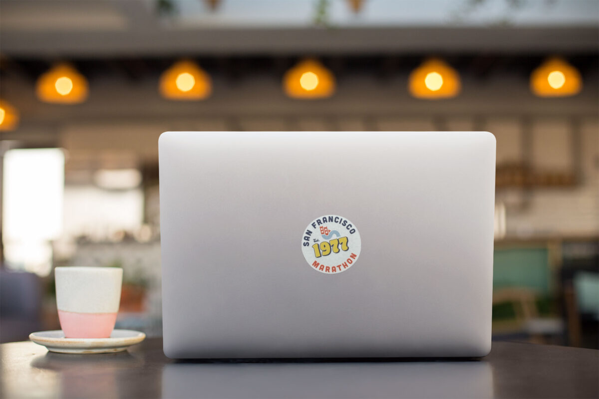 3 inch vinyl sticker with San Francisco Marathon design on laptop in a cafe