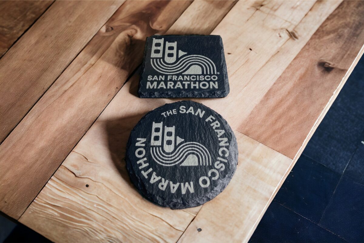 Two San Francisco Marathon slate coasters on a wooden countertop